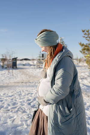 Pregnant woman standing in the park on a sunny winter dayの写真素材