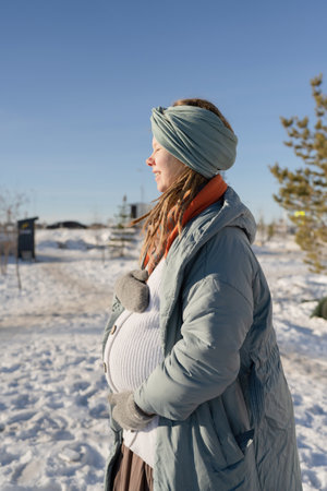 Pregnant woman standing in the park on a sunny winter dayの写真素材