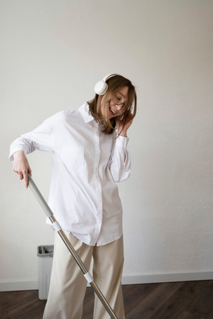 Happy young woman doing house cleaning, dancing and singingの写真素材