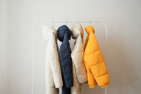 Colorful winter clothes on hangers against white wall. winter clothingの写真素材