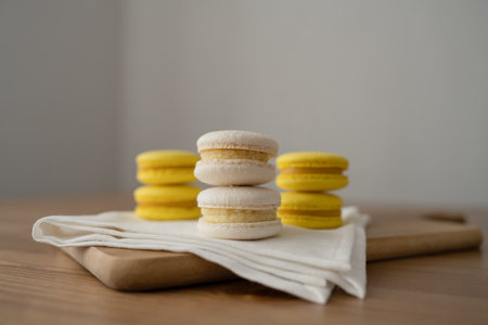 Yellow and white macarons on a wooden table.の写真素材