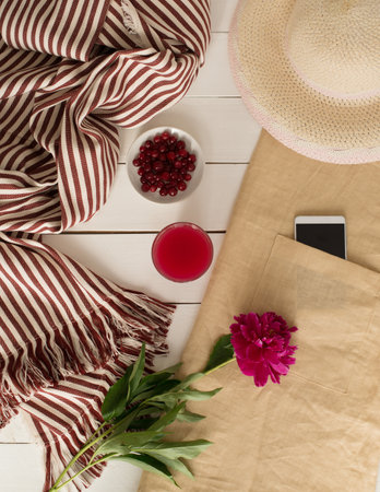 Flat lay, top view summer composition with bag, smartphone and peony flowers on white wooden background.の写真素材