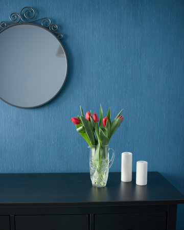 Bouquet of red tulips in glass vase on black table against blue wallの写真素材