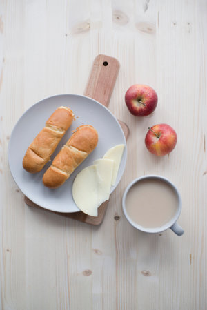Breakfast with coffee, buns and cheese on wooden tableの写真素材