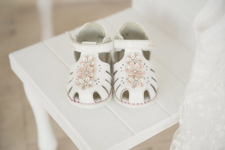Beautiful child shoes for the bride and groom on a white chairの写真素材