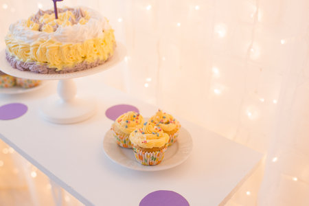 Birthday cupcakes on a white table with lights in the backgroundの写真素材
