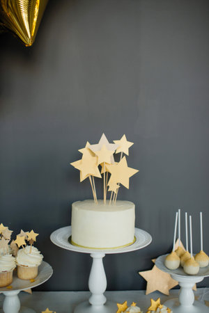 Birthday cake with stars on a white stand against a gray wall