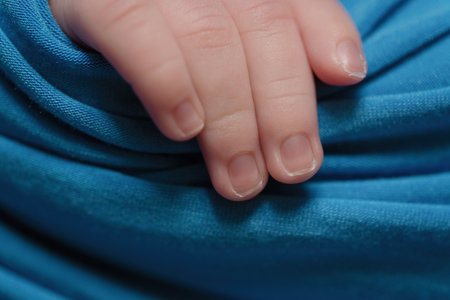 Baby's hand on blue satin background, close-up shotの写真素材