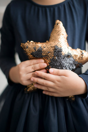 A little girl in a black dress holds a star in her handsの写真素材