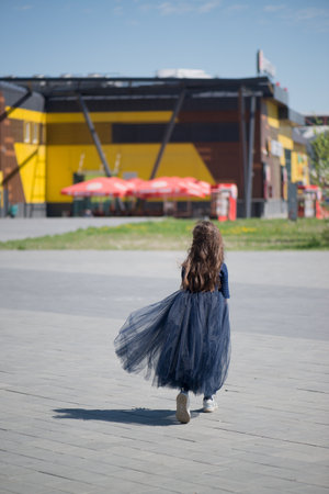 Unrecognizable little girl in a blue dress on the background of the city.の写真素材