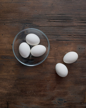 White eggs in a glass bowl on a wooden background. top view.の写真素材