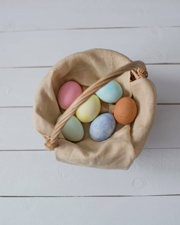 Easter eggs in a basket on a white wooden background. top view.
