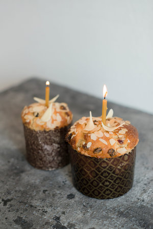 Two Easter cake with almonds and a burning candle on a gray background