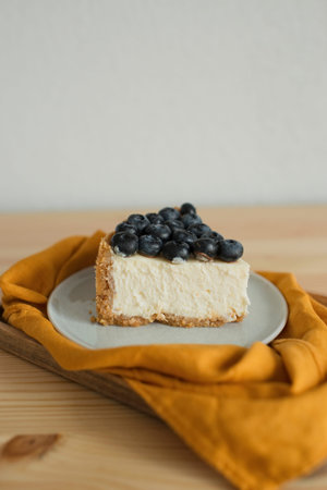 Blueberry cheesecake on white plate on wooden table with copy space