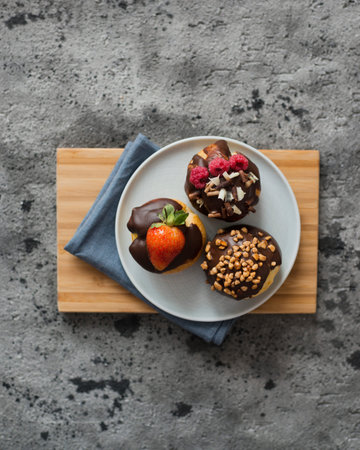 Chocolate muffins with strawberries and chocolate sprinkles on wooden board