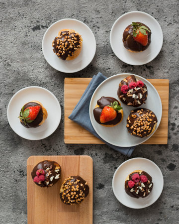 Chocolate muffins with strawberries and nuts on a gray concrete background