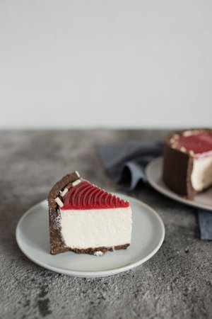 Slice of cheesecake with red velvet cake on gray background.