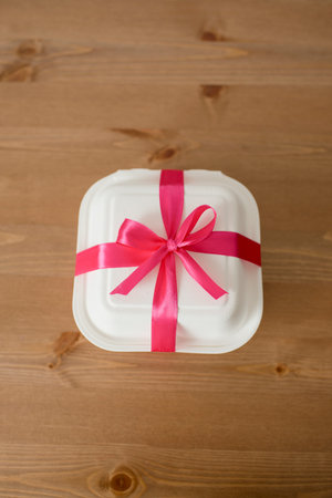 White gift box with red bow on wooden background. top view.の写真素材