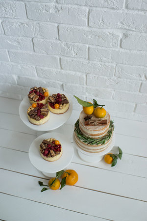 Cake decorated with tangerines and rosemary on a white background