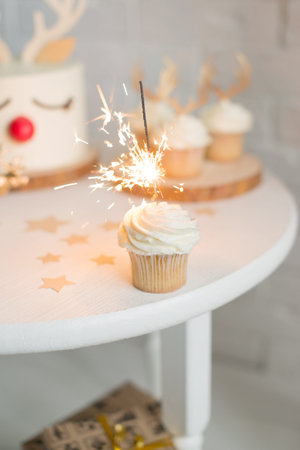 Cupcake with a sparkler on a white table with giftsの写真素材