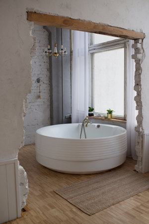 Interior of modern bathroom with white bathtub and windowの写真素材