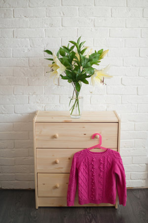 Beautiful bouquet of lilies on chest of drawers in room