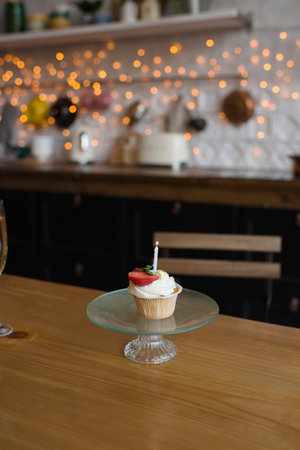 Delicious cupcake with cream and strawberry on table in modern kitchenの写真素材