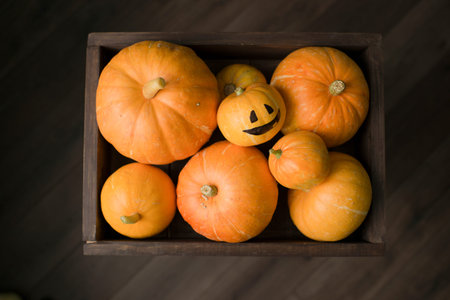 Halloween pumpkins in a wooden box on a wooden background.の写真素材