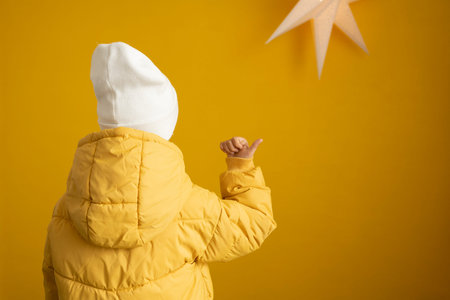 Child in a yellow jacket on a yellow background with a star.