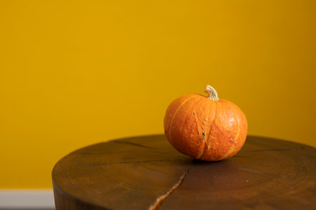 Pumpkin on a wooden table against a yellow wall with copy spaceの写真素材