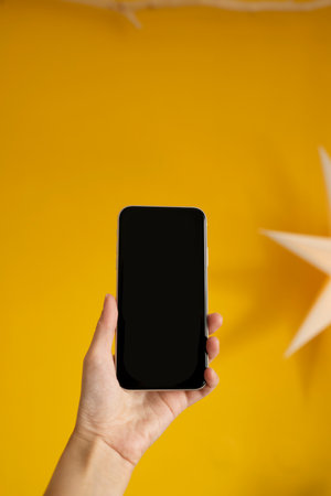 Smartphone mockup with blank screen in woman hand on yellow backgroundの写真素材