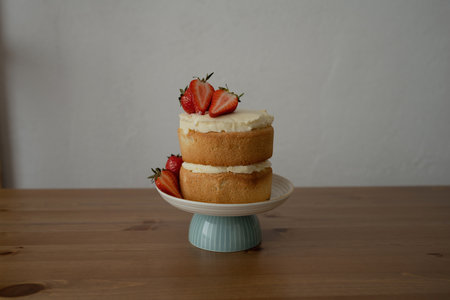 Strawberry cake on a plate on a wooden table and white wall backgroundの写真素材