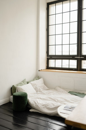 Interior of a modern bedroom with white walls, black wooden floor and big windowの写真素材