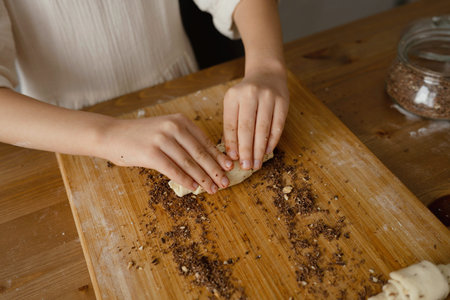 Close-up of the dough prepared by the hands of a child on a wooden board