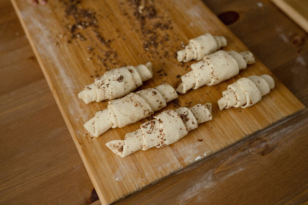 Preparation of puff pastry rolls with chocolate on a wooden boardの写真素材