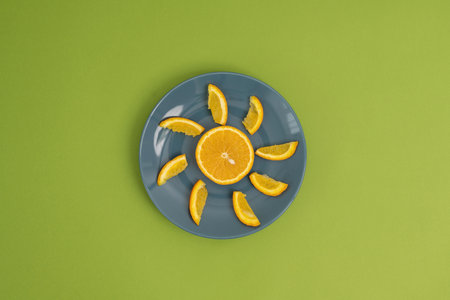 Orange slices on a blue plate on a green background, top viewの写真素材
