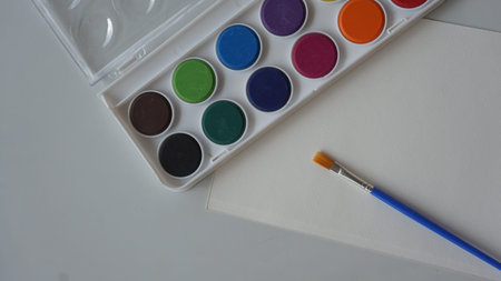 Watercolor paints and brush on a white background. Selective focus.