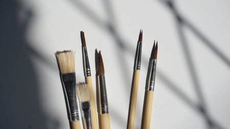 Paint brushes on a white background with shadows from the window.