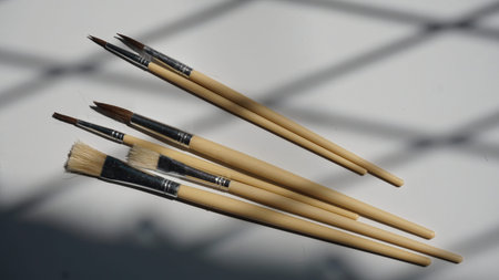 Paint brushes on a white background with a shadow from a window