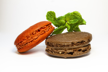 colorful macaroon cookies red and brown with mint leaf on white backgroundの写真素材
