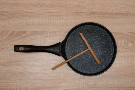 new black pan for baking pancakes with a wooden spatula top view on a wooden background, tableの写真素材