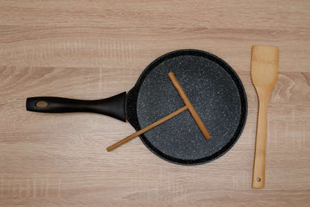 new black pan for baking pancakes with a wooden spatula top view on a wooden background, tableの写真素材