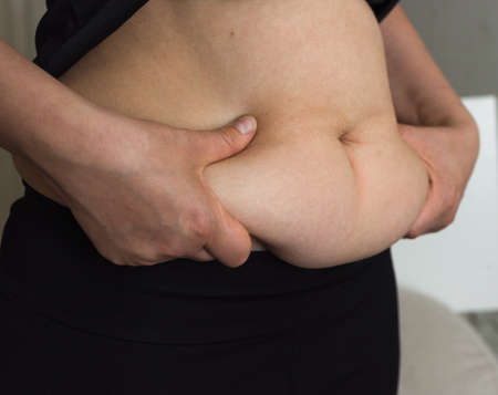 obesity women big belly. Fat woman measuring isolated. Woman with fat belly, overweight female body isolated on white background, close-upの写真素材