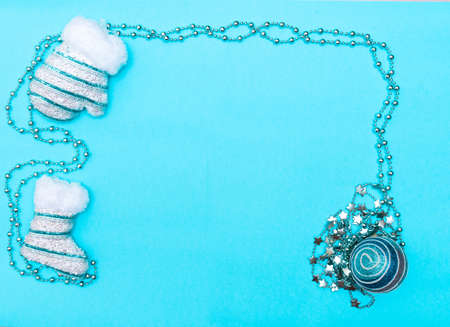 Christmas and New Year concept layout. Mittens, beads and a Christmas ball on a blue background, top view, frame, place for the text.の写真素材