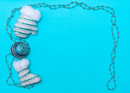 Christmas and New Year concept layout. Mittens, beads and a Christmas ball on a blue background, top view, frame, place for the text.の写真素材