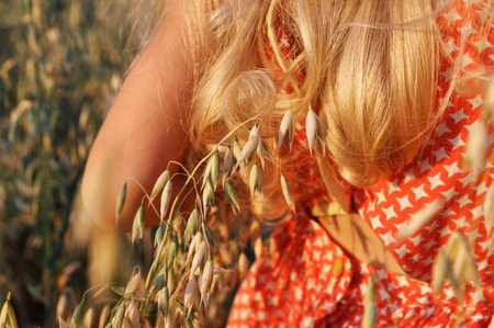 girl with curly long hair walking on the field with oats at sunset. summer. vintage. adventuresの写真素材