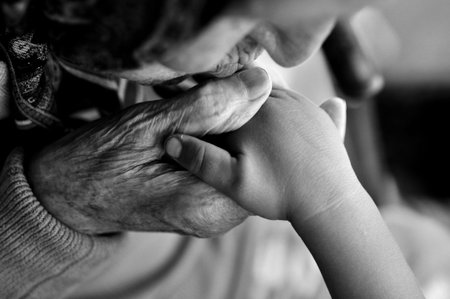 an elderly woman kissing children's hands. Summer walk on the street. 1 year and 90 years. holiday....