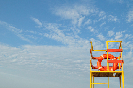Orange lifeline on yellow lifeguard tower on blue sky background. Horizontal.の写真素材