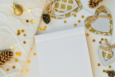 Cozy magical Christmas background for writing on a blank sheet of notebook on white with cones, sweater, stars and decor. Top view.の写真素材