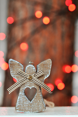 Cute wooden angel decoration on the Christmas tree on the background of red lights on the streetの写真素材